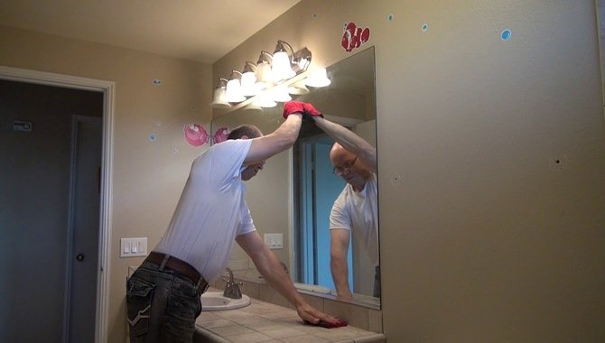 Using A Crowbar To Remove A Mirror Glued To Wood
